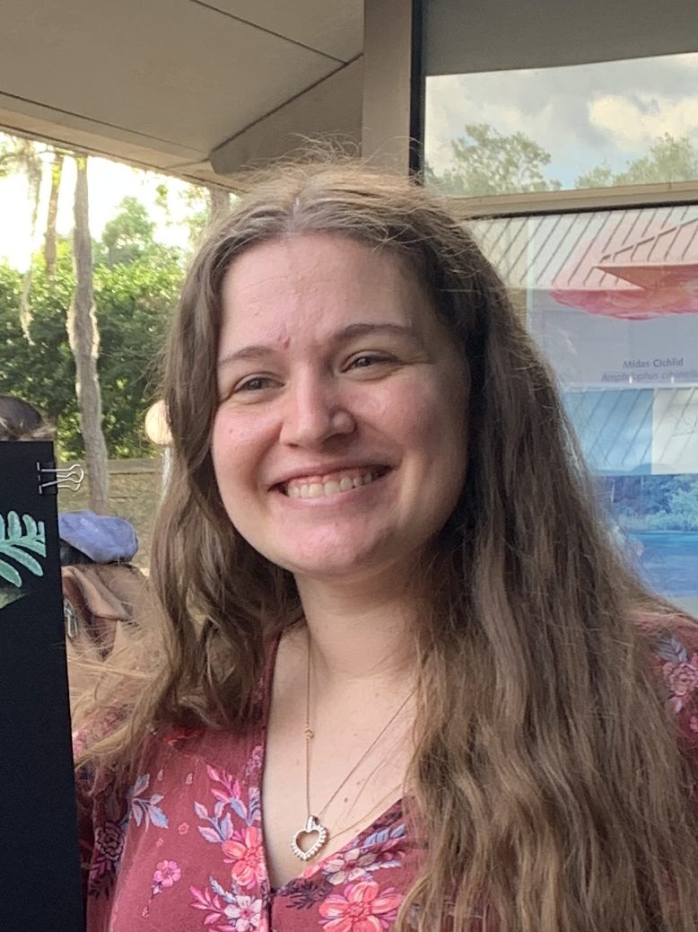 Woman with long brown hair smiles outdoors.
